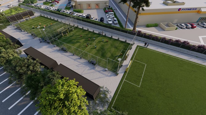 Aerial view of a soccer court with players in action beside a fitness center.