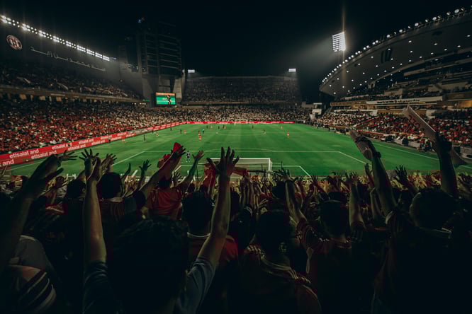 Fans cheering in a packed soccer stadium during a night match