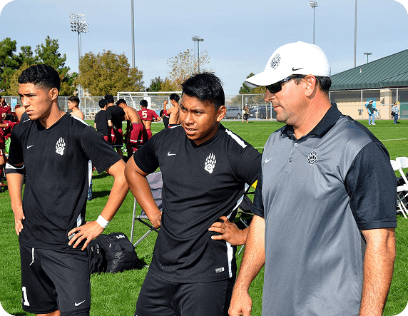 Coaches and players discussing game strategy on the sideline at Fusion Sports Park