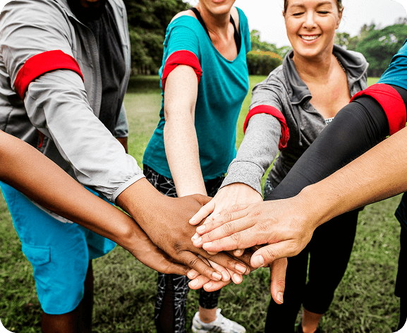 Group huddle with stacked hands symbolizing teamwork, inclusion, and community spirit at Fusion Sports Park