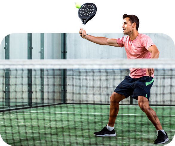 Man playing padel on an indoor court, preparing to hit the ball with his racket