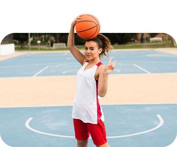Young girl holding a basketball on an outdoor court with a confident pose