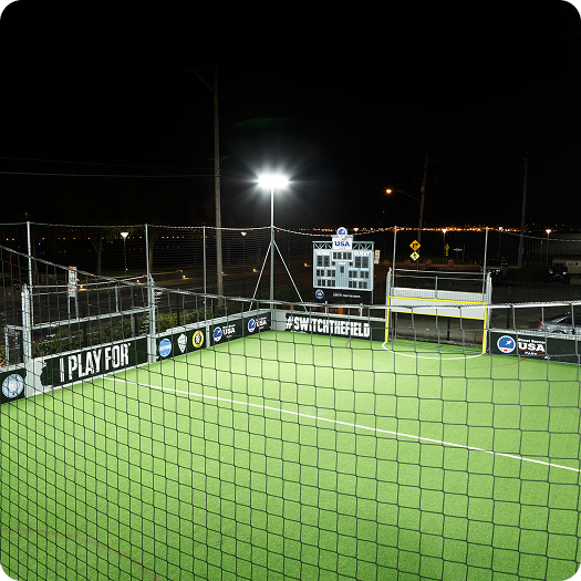 Mini soccer pitch illuminated at night with bright floodlights at Fusion Sports Park, showcasing safe evening play.